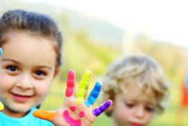 A little girl holding up her hand with paint on it.